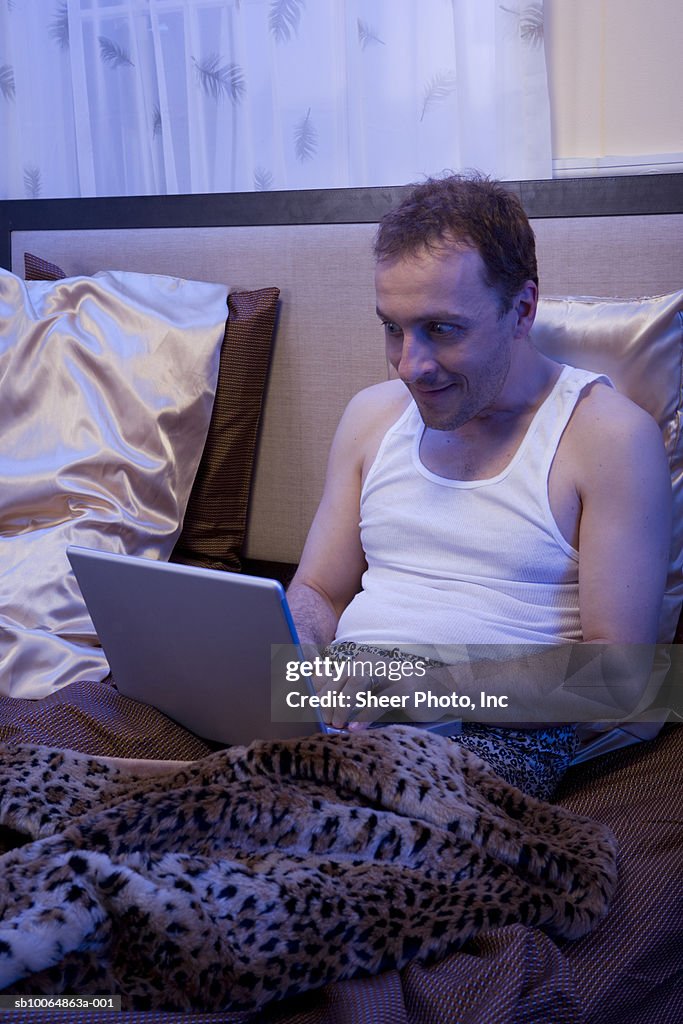 Man using laptop in bed