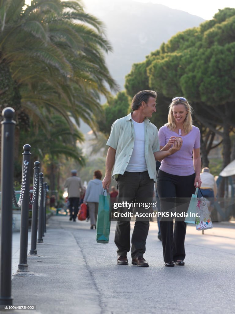 Mature couple carrying shopping bags along promenade