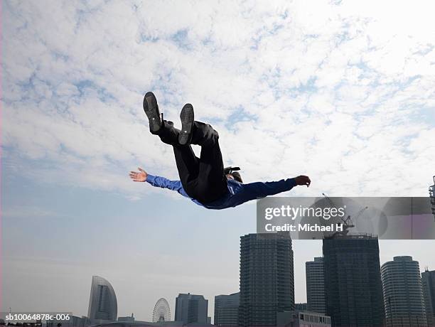 businessman jumping in air, skyscrapers in background, low angle view - person falling mid air stock pictures, royalty-free photos & images