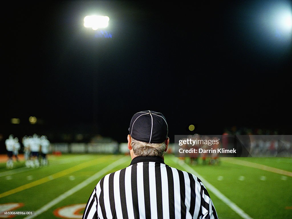 American football referee on field, rear view