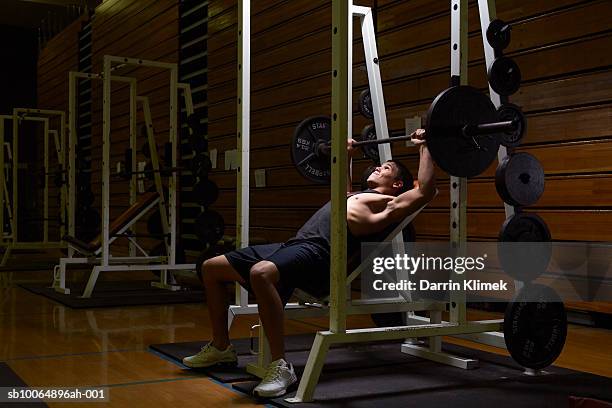 teenage boy (16-17) practicing in health club - sollevamento pesi foto e immagini stock