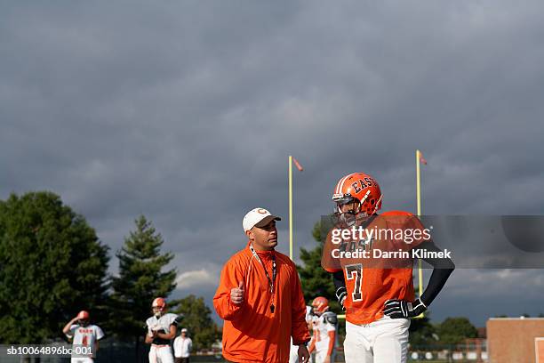 teenage (16-17) american football player talking with coach - american football coach stock-fotos und bilder