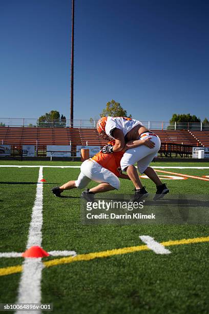 american football players (15-17) wrestling in field - placcare foto e immagini stock