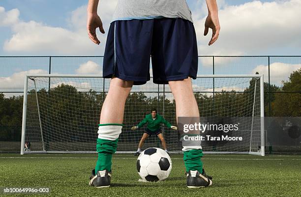 goalie waiting and player with ball in front of goal post, rear view, low section - breitbeinig stehen stock-fotos und bilder