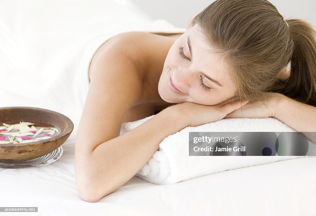 Young woman relaxing on massage table, smiling