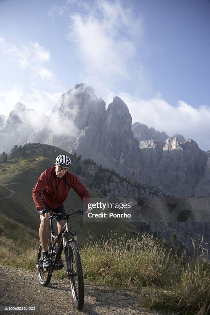 Italy, Tyrol, senior biker riding on mountain ridge