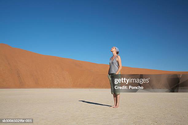 namibia, woman looking up standing on desert, side view - desert sky stock pictures, royalty-free photos & images