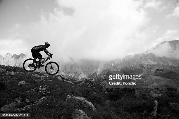 italy, tyrol, senior biker riding on mountain edge, side view - landscape black and white stockfoto's en -beelden