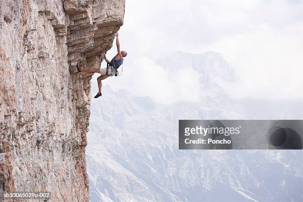 italy, tyrol, senior man climbing rock - klettergarten stock-fotos und bilder