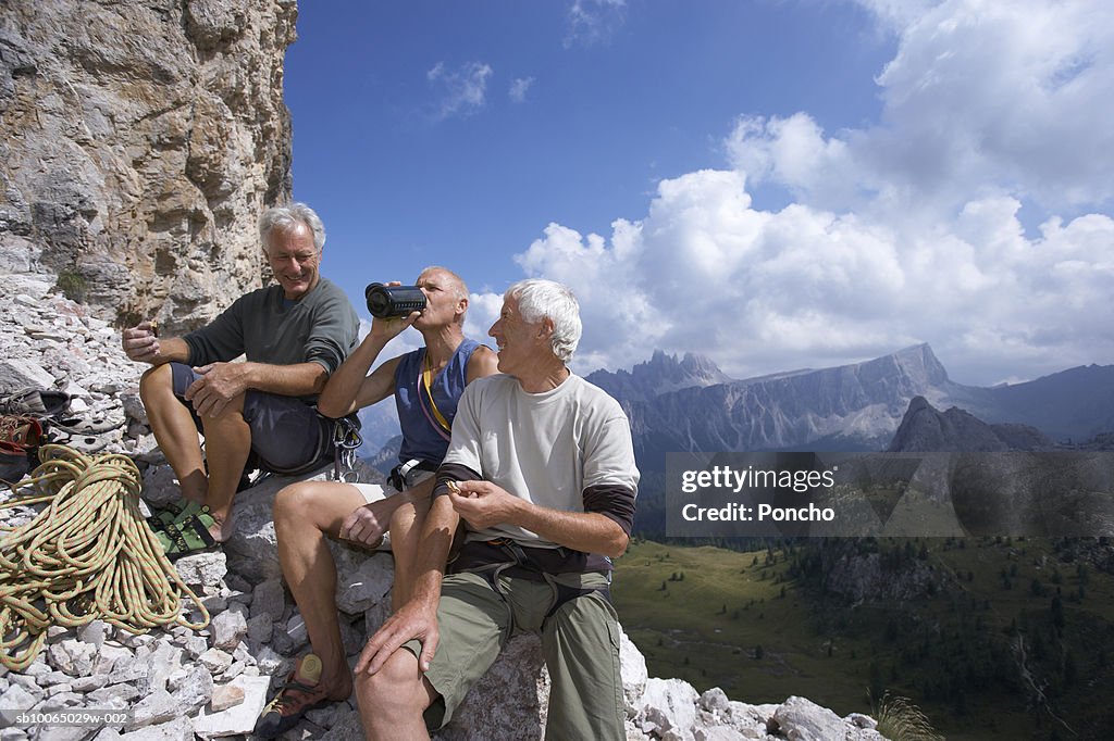 Italy, Tyrol, three senior hikers sitting on mountain edge