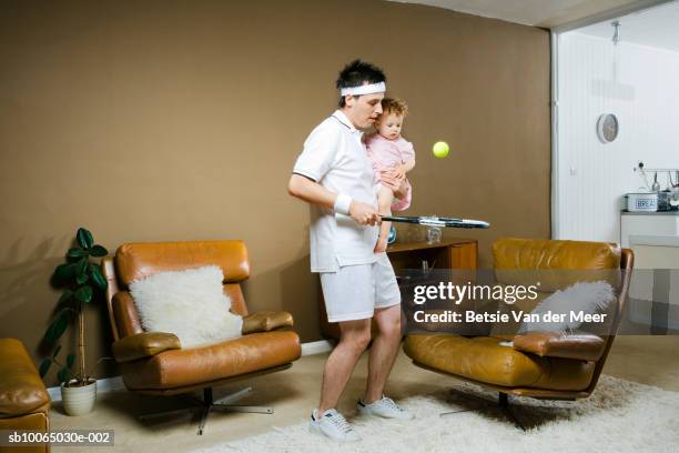 father holding daughter (9-12 months) and playing tennis - sports man cave stock pictures, royalty-free photos & images