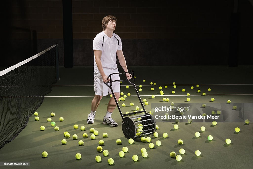Young man collecting tennis ball from tennis court