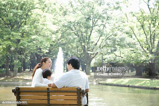 couple with son (6-9 months) relaxing in park on bench, rear view - sb10065036cb 001 stock pictures, royalty-free photos & images