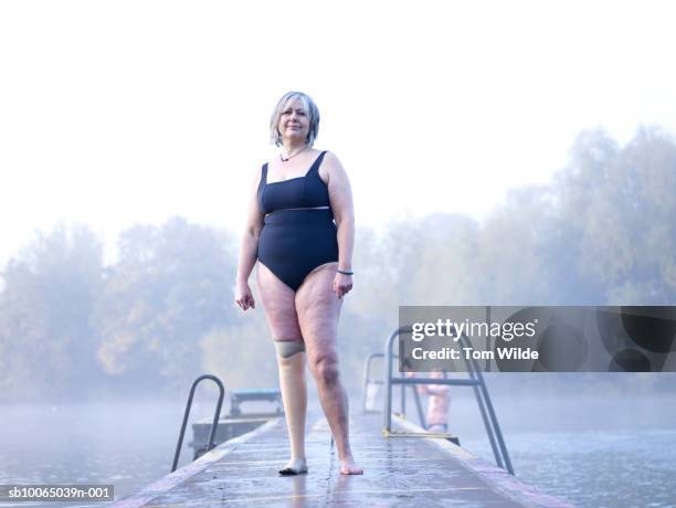 female swimmer with prosthetic leg standing on jetty, portrait - disabilitycollection fotografías e imágenes de stock