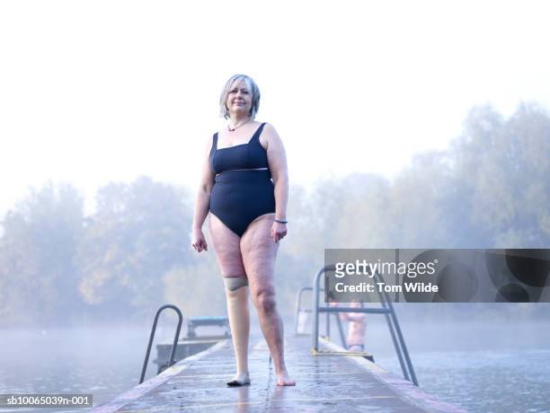 Female swimmer with prosthetic leg standing on jetty, portrait
