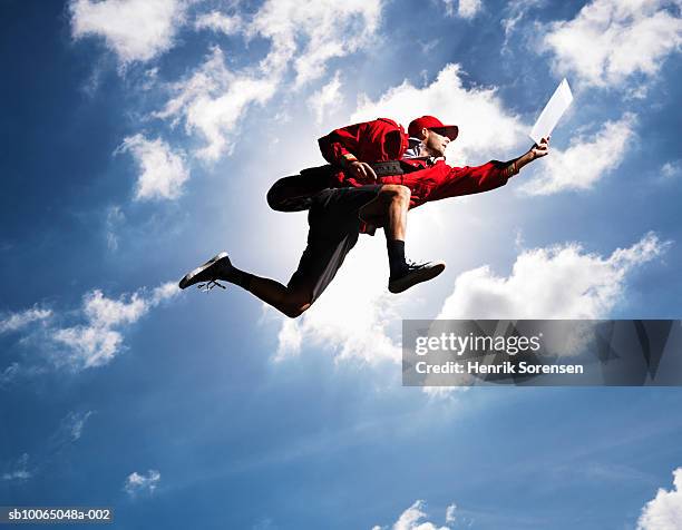man flying in air with letter in hand, against sky, low angle view - postino foto e immagini stock
