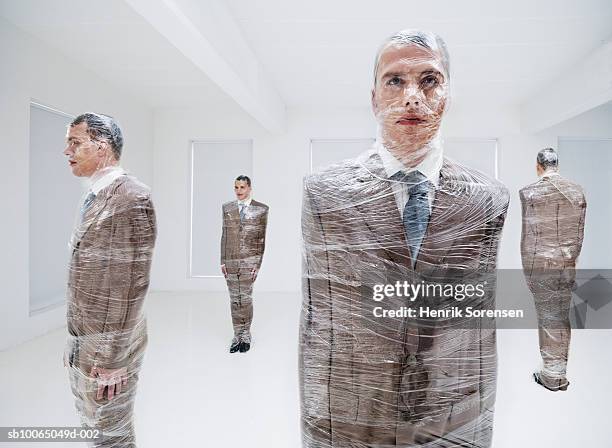 four businessmen wrapped in plastic wrap (digital composite) - man wrapped in plastic stock pictures, royalty-free photos & images