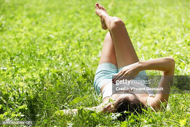 young woman sunbathing in grass - allongé sur le dos photos et images de collection