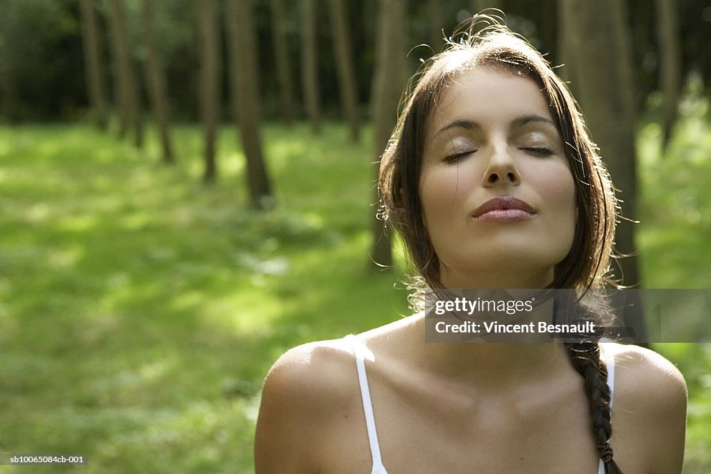 Close-up of young woman in forest, eyes closed