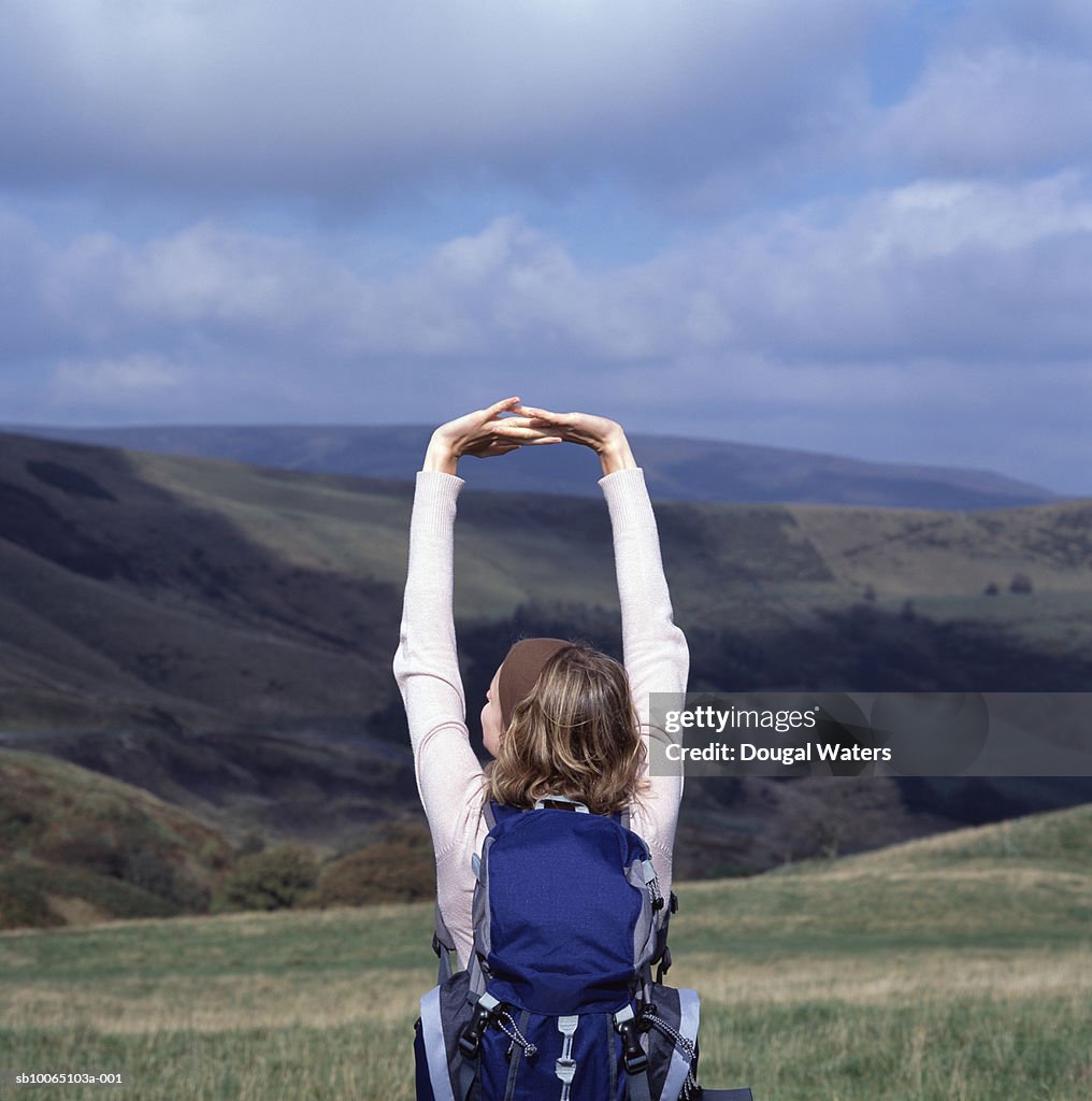 Young female hiker stretching arms in landscape