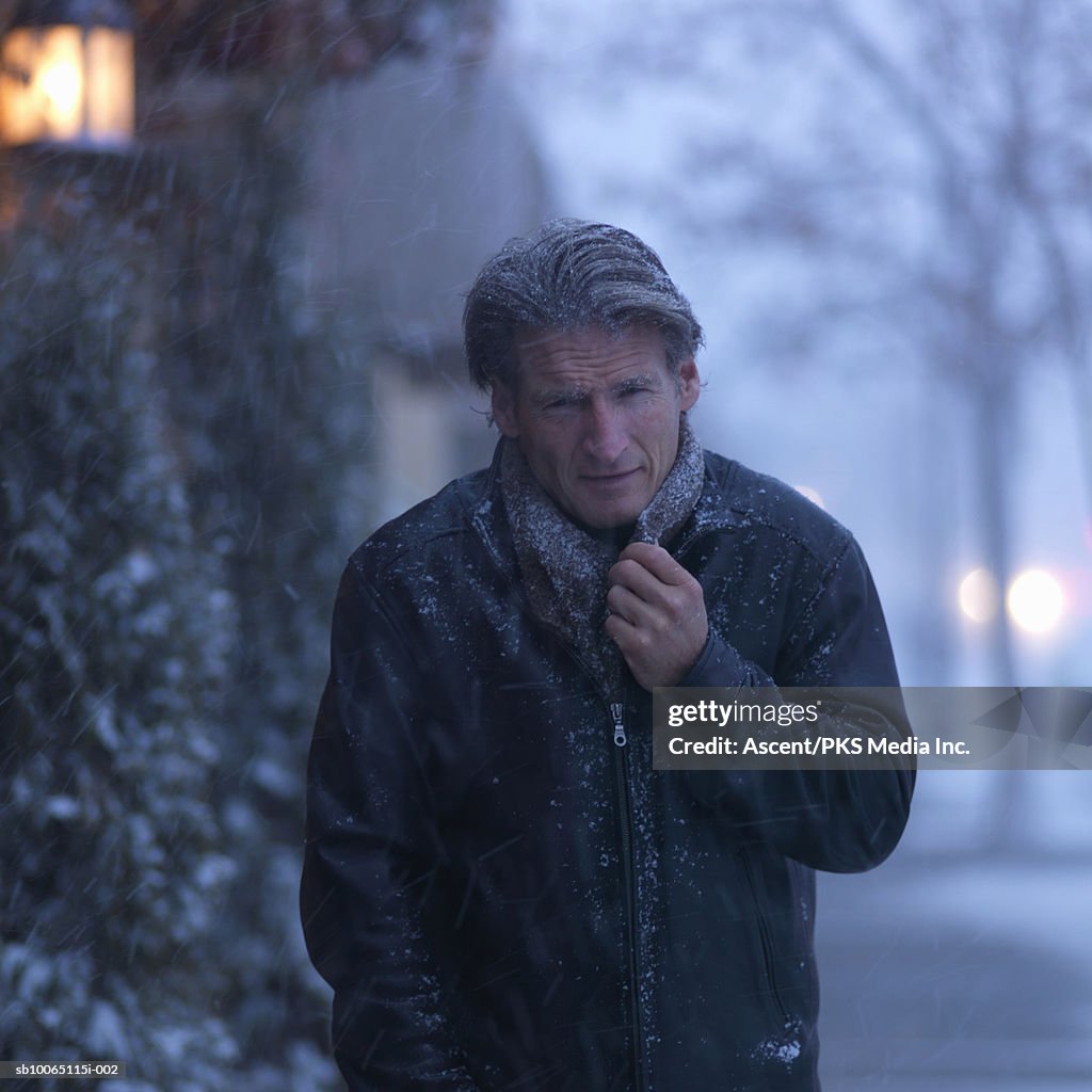 Mature man wearing winter coat in blizzard, portrait, (focus on foreground)