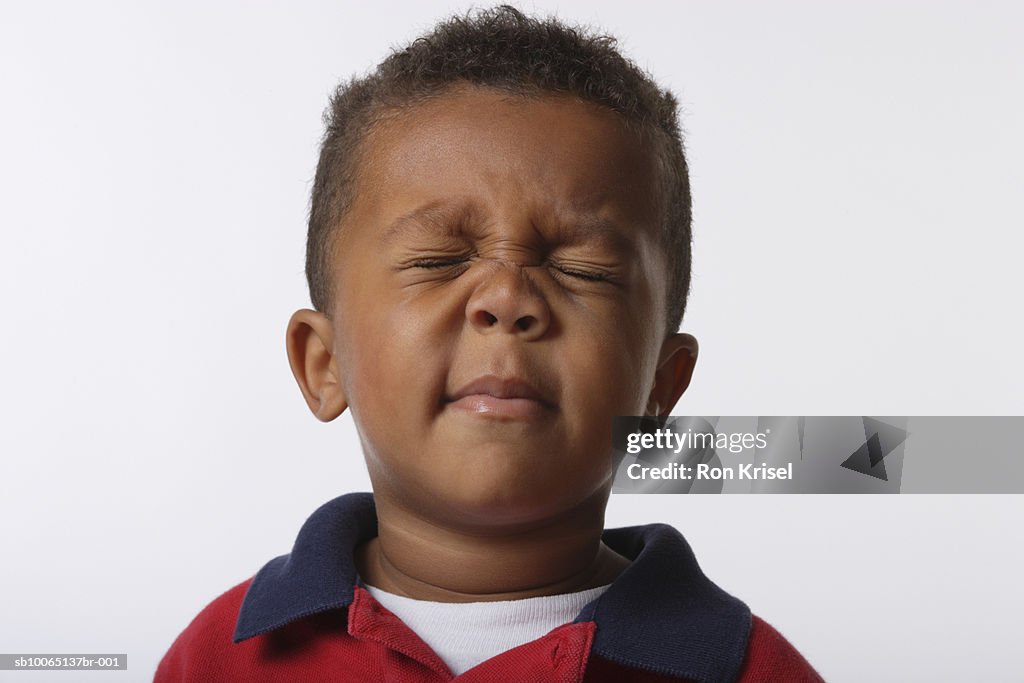 Boy (4-5) frowning with eyes shut, close-up