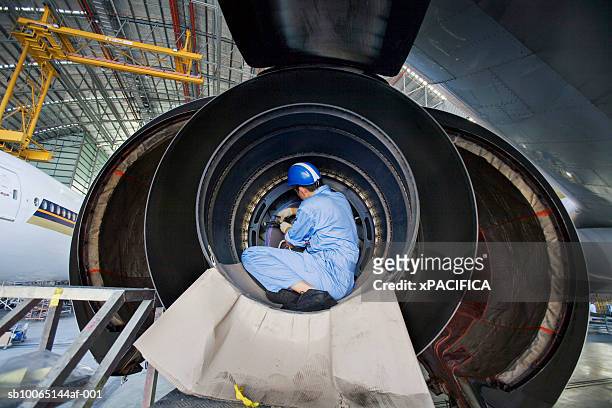 engineer working at aviation maintenance facility, rear view - aerospace stockfoto's en -beelden