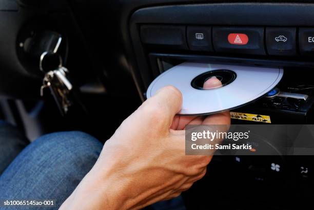 mature man inserting compact disc into car stereo, close-up of hand - compact disc fotografías e imágenes de stock