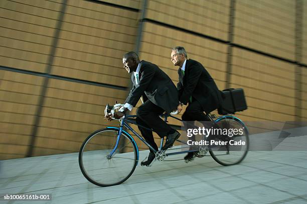 two business men riding on tandem bike, side view - tandem bicycle foto e immagini stock