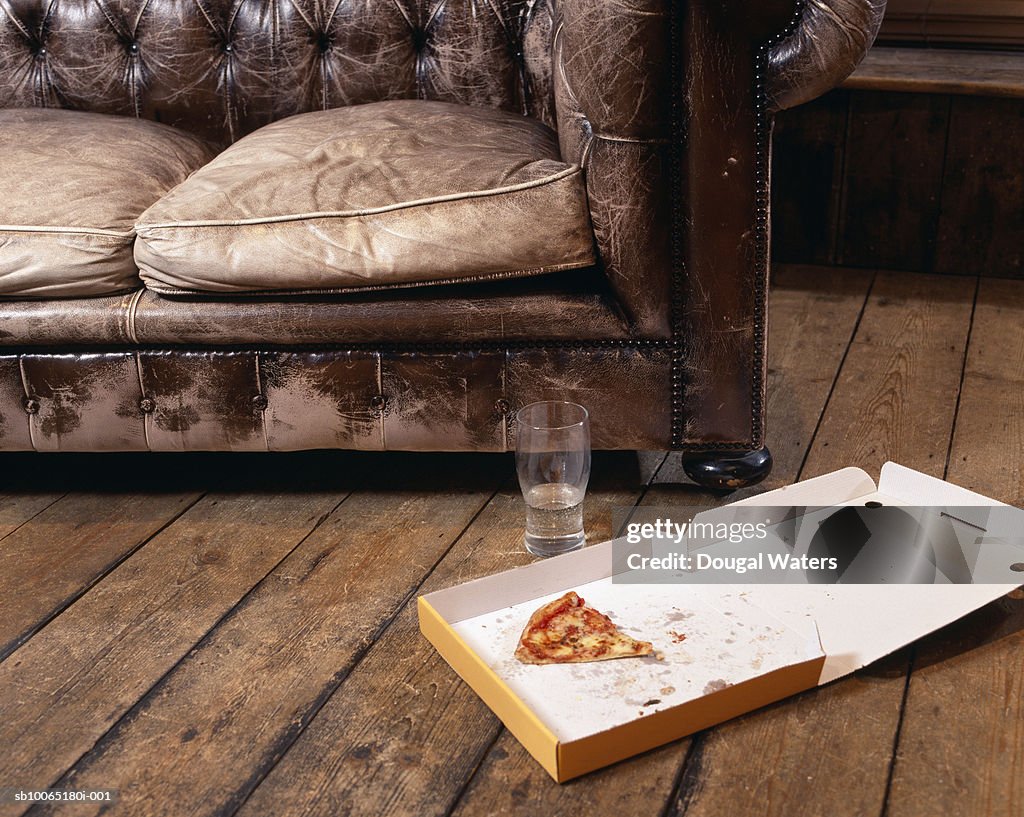 Slice of pizza in box on floor in living room