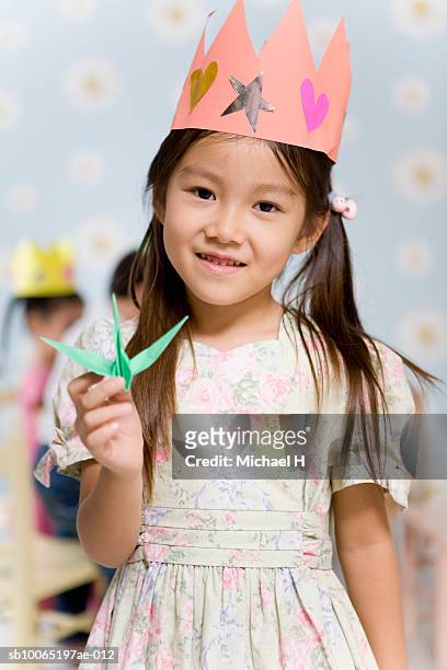 girl (4-5) wearing paper crown, holding origami piece, portrait - paper crown stock pictures, royalty-free photos & images