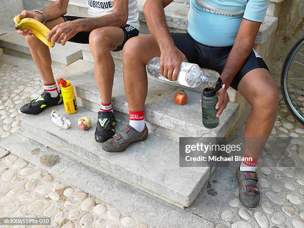 two cyclists sitting on steps, having lunch, low section - cyklist bildbanksfoton och bilder