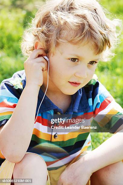 boy (6-7 years) wearing earphones, sitting on grass - boys only caucasian ethnicity 6 7 years stock pictures, royalty-free photos & images