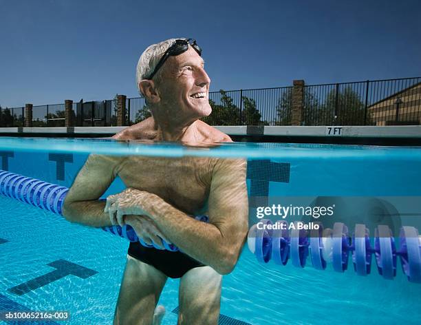 senior man in swimming pool, leaning on swimming lane marker - swimming lane marker foto e immagini stock