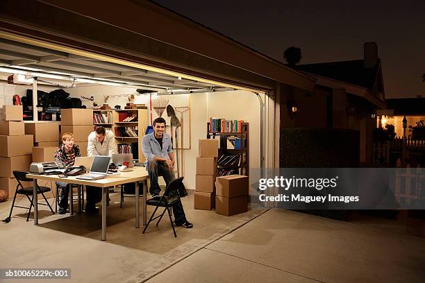 three men working at laptops on desk in garage at night - gardien de but fotografías e imágenes de stock