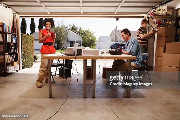 two men and woman in office space in garage - business start up stock pictures, royalty-free photos & images
