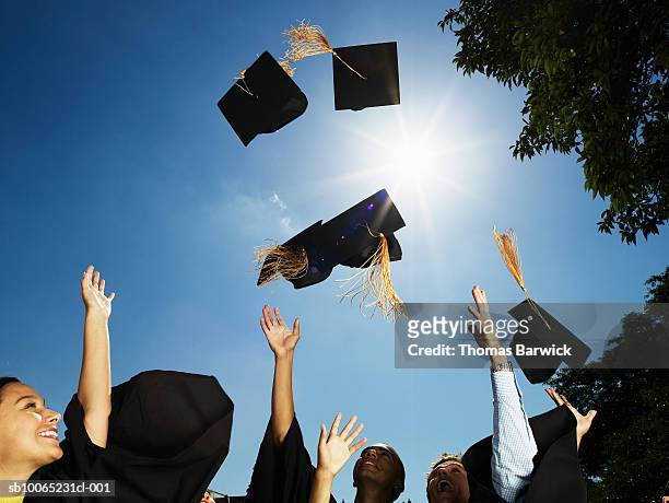group of graduates throwing mortar boards in air - throwing stock pictures, royalty-free photos & images