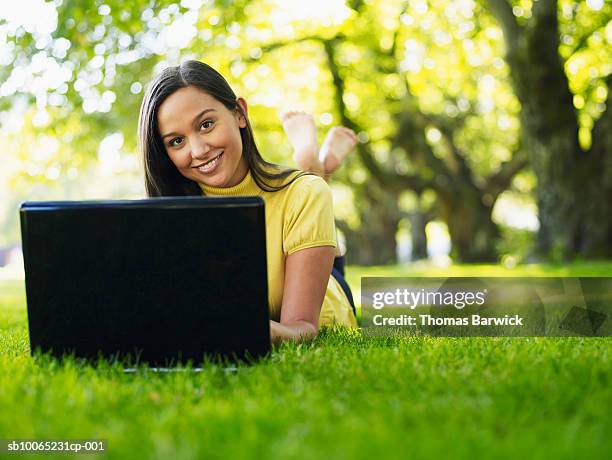 portrait of female college student lying on grass working on laptop (surface level) - laying park stock pictures, royalty-free photos & images