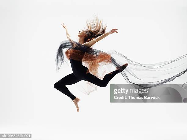 female dancer leaping in mid air against white background, side view - effortless stock-fotos und bilder