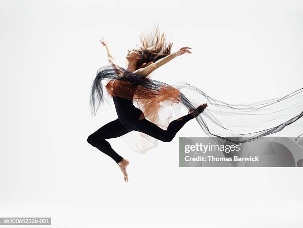 female dancer leaping in mid air against white background, side view - agility studio shot stock pictures, royalty-free photos & images