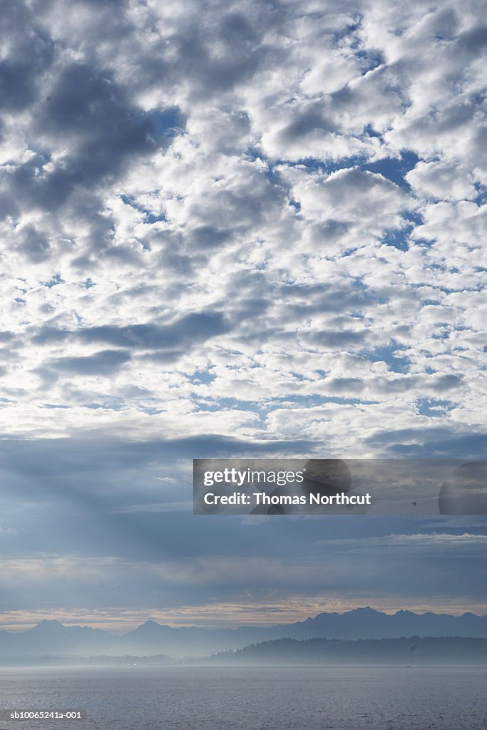 Clouds over lake with mountain range in background