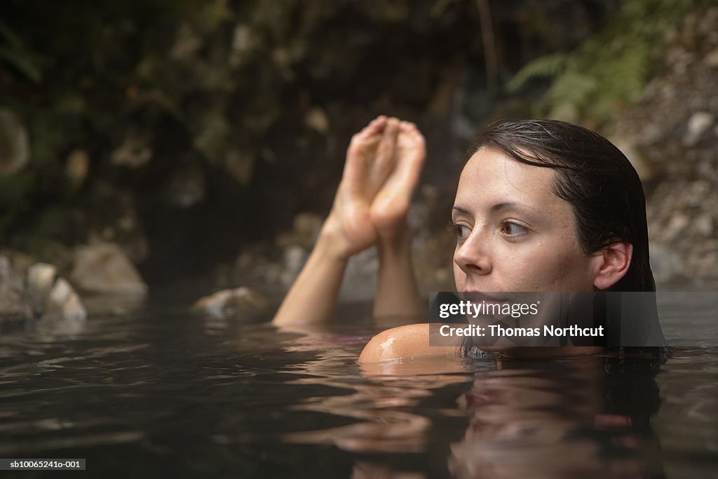 Close-up of young woman lying in hot spring waters