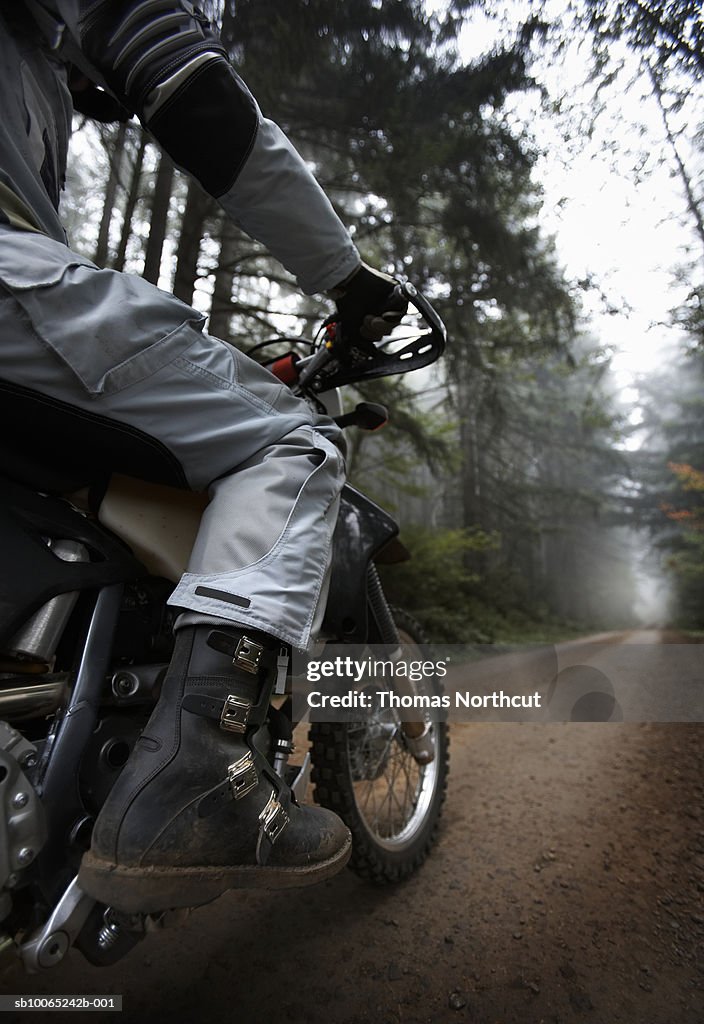 Mature biker riding in forest, low section