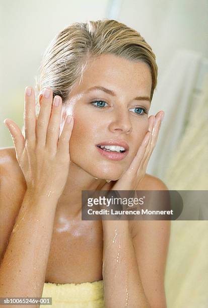 young woman touching her cheeks and looking at herself in mirror - miroir stock pictures, royalty-free photos & images