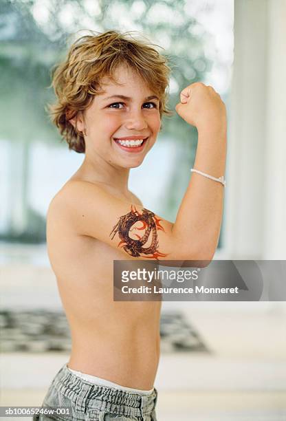 boy (8-9) showing his biceps tattooed with dragon, smiling - white dragon tattoo stock pictures, royalty-free photos & images