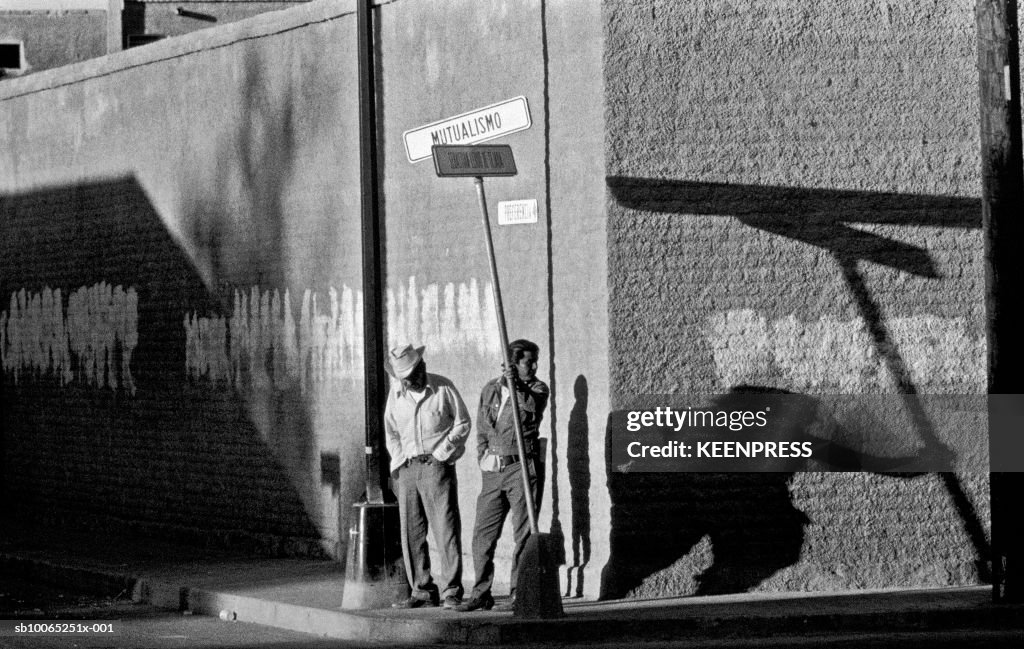 Men standing on street corner at sunrise