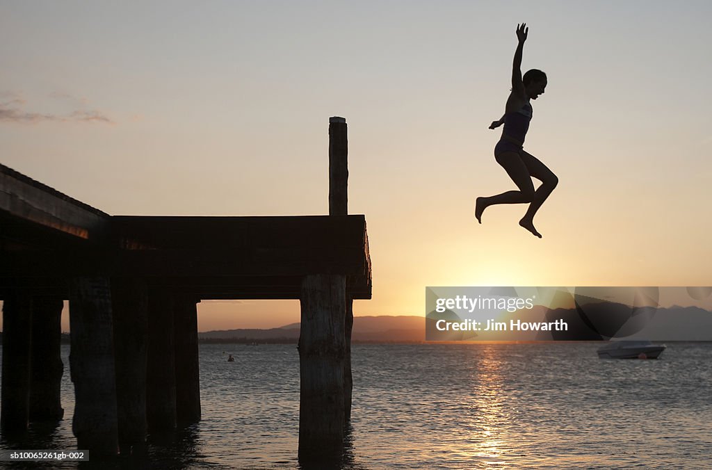 Girl jumps off a jetty into Lake Garda, Peschiera, Italy