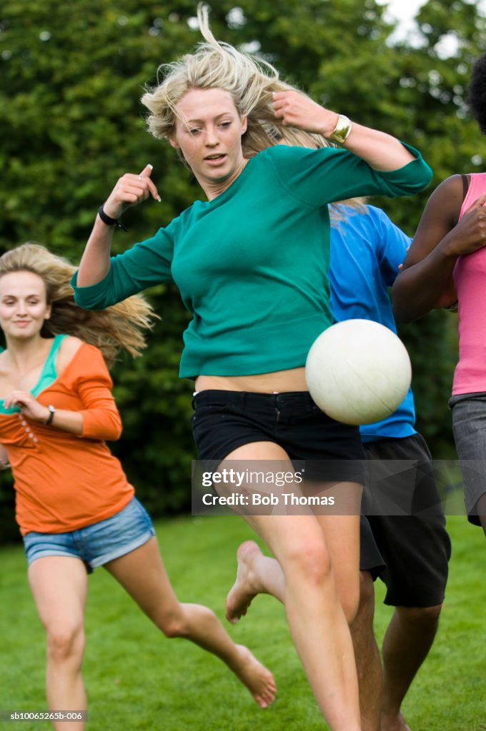 Teenage girl (16-17) with young woman playing soccer ball