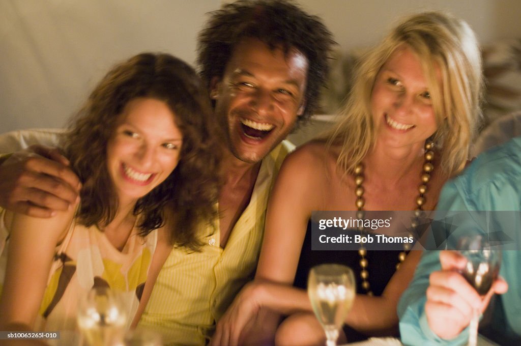 Man with two young women, looking away, laughing