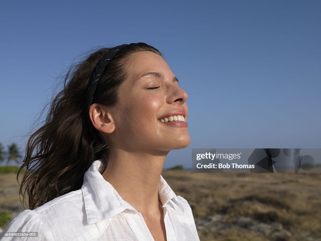 Young woman smiling, eyes closed, side view
